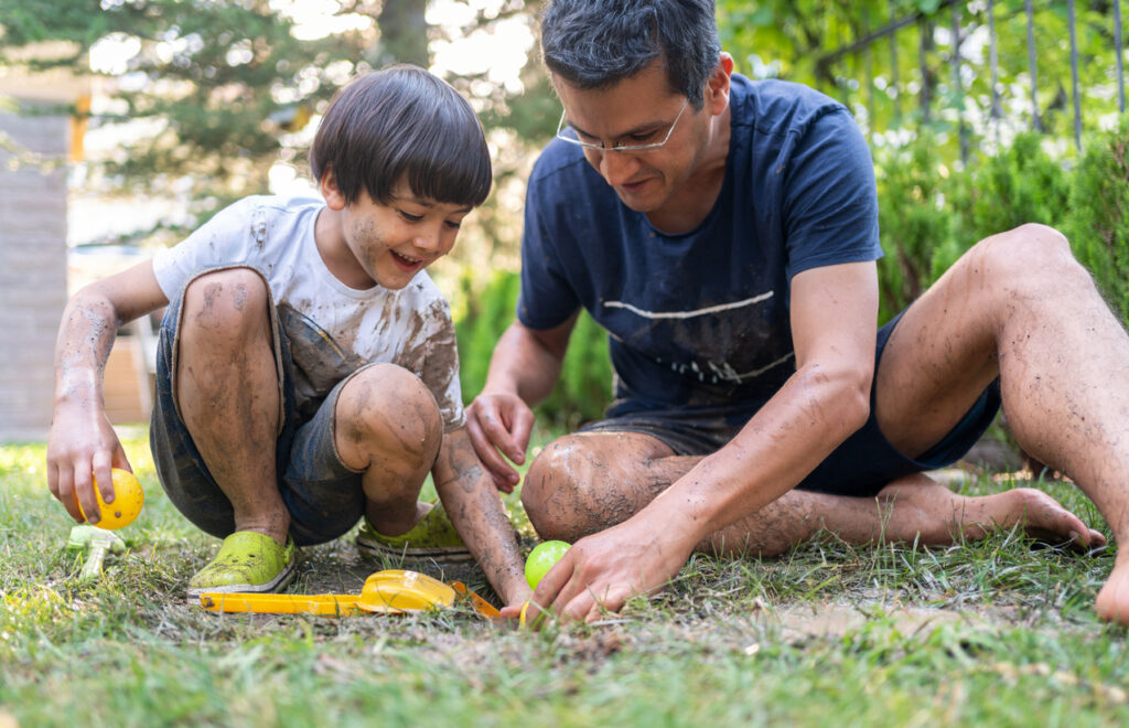 Muddy father and son planting seeds in the yard.