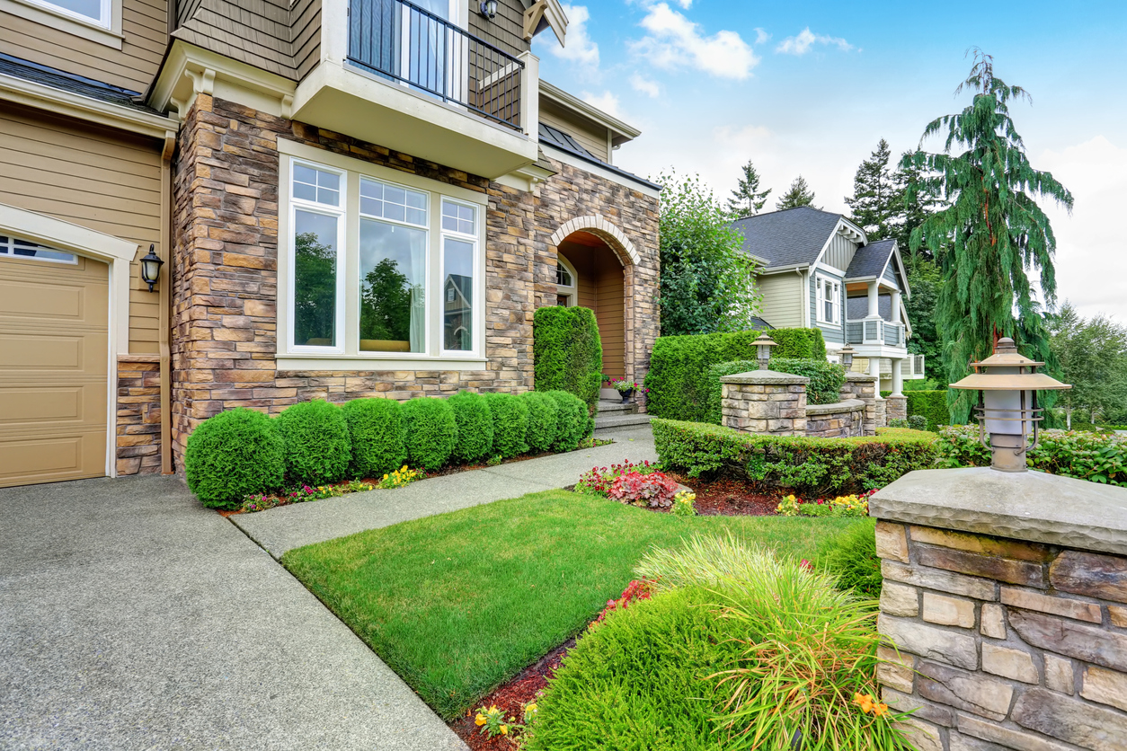 Home's curb appeal - Beautiful landscape of an American house featuring stone trim.