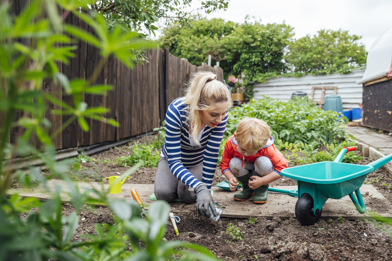 Mother and son planting seeds in their home's backyard.
